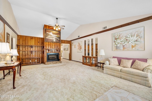 carpeted living room with ceiling fan, wood walls, and vaulted ceiling