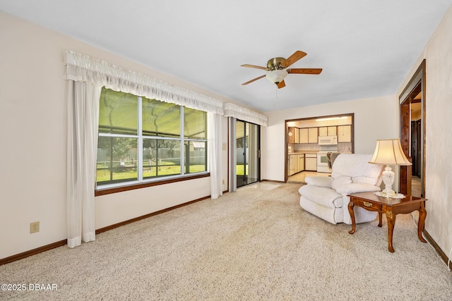 living area with light carpet and ceiling fan