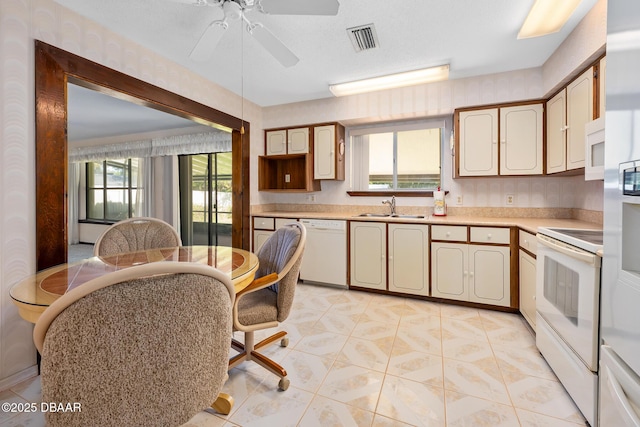 kitchen featuring white appliances, ceiling fan, sink, cream cabinets, and light tile patterned flooring