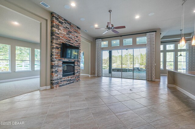 unfurnished living room with a healthy amount of sunlight, a large fireplace, light tile patterned floors, and visible vents