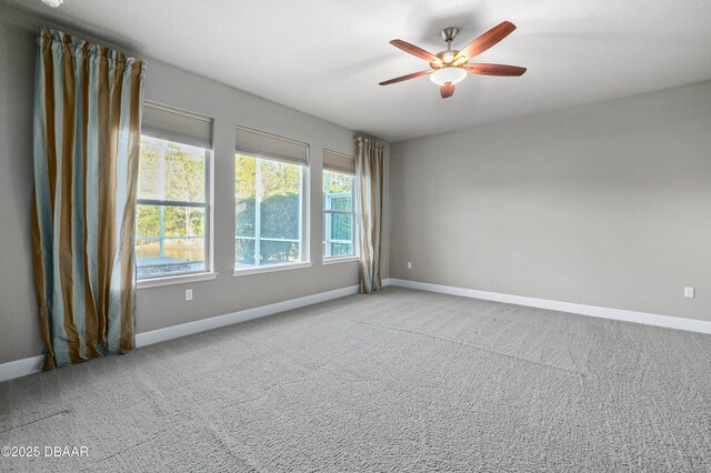 empty room featuring baseboards, ceiling fan, and light colored carpet