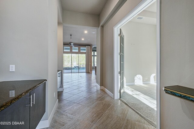 hall featuring visible vents and baseboards