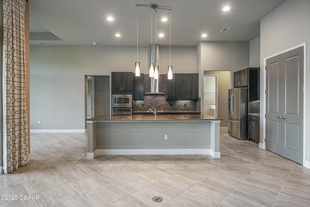 kitchen with visible vents, hanging light fixtures, appliances with stainless steel finishes, dark brown cabinets, and an island with sink