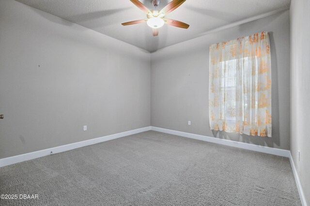 carpeted spare room with a ceiling fan and baseboards