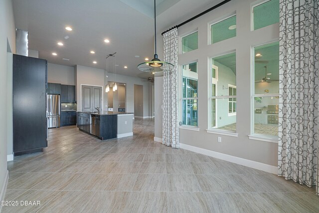 kitchen with a center island with sink, open floor plan, freestanding refrigerator, hanging light fixtures, and a sink