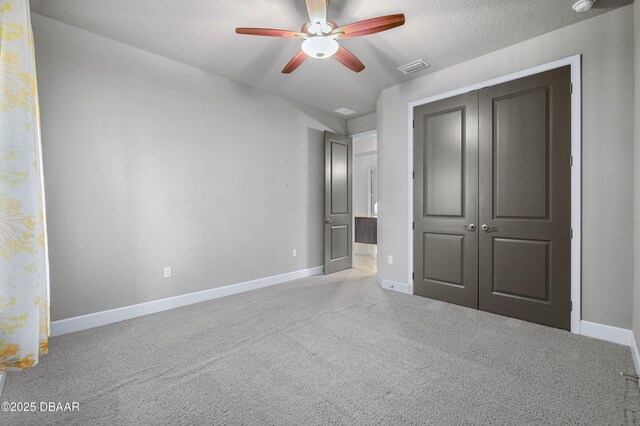 unfurnished bedroom featuring baseboards, visible vents, a textured ceiling, carpet floors, and a closet