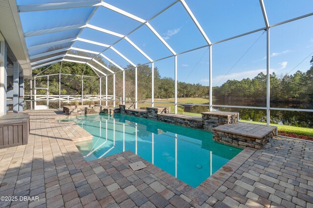 outdoor pool featuring glass enclosure, a patio area, and a water view