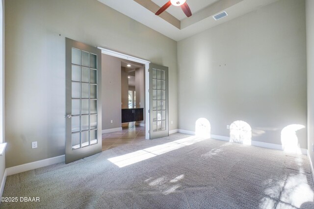 unfurnished room featuring french doors, visible vents, a ceiling fan, light carpet, and baseboards