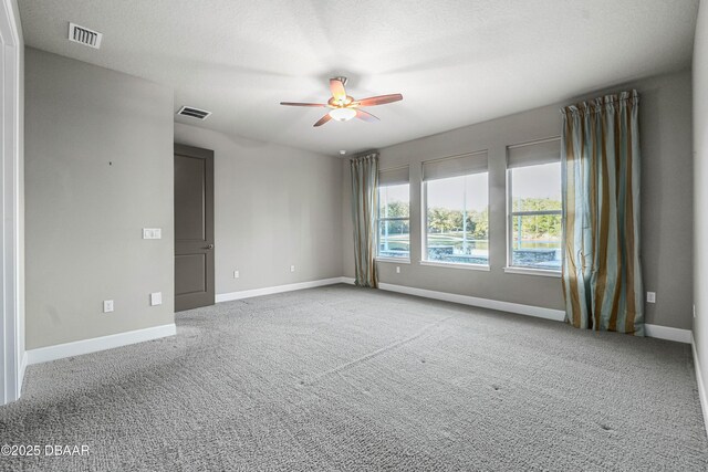 carpeted spare room featuring visible vents, ceiling fan, a textured ceiling, and baseboards