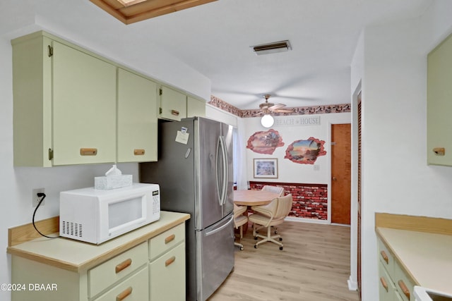 kitchen featuring ceiling fan, light hardwood / wood-style floors, green cabinets, and stainless steel refrigerator