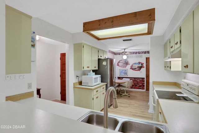 kitchen with kitchen peninsula, white appliances, sink, and light hardwood / wood-style flooring