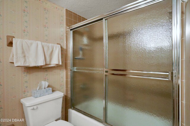 bathroom featuring toilet and bath / shower combo with glass door