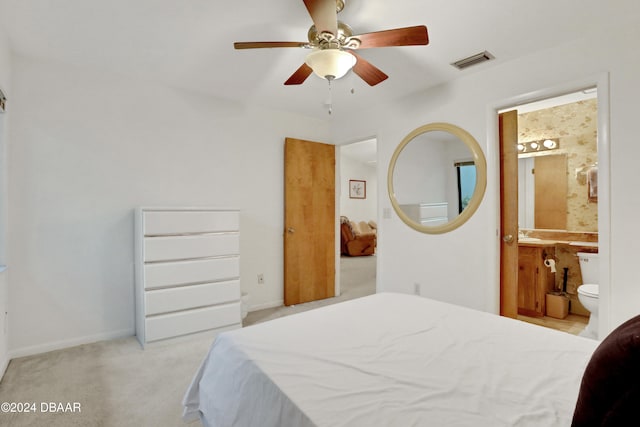 bedroom with connected bathroom, light colored carpet, and ceiling fan