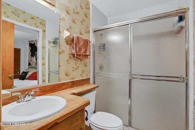 bathroom with a shower with door, vanity, and toilet