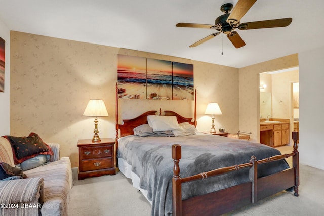 bedroom featuring sink, ceiling fan, light colored carpet, and ensuite bathroom