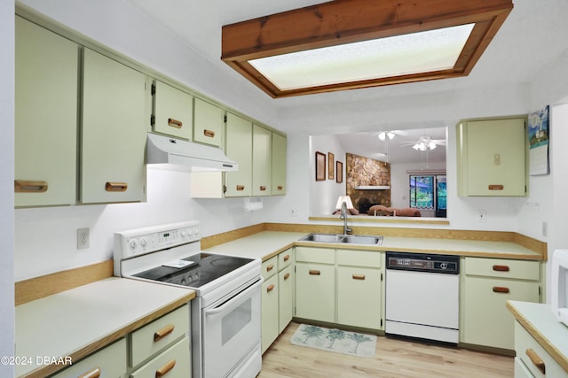 kitchen with light wood-type flooring, white appliances, sink, and green cabinetry