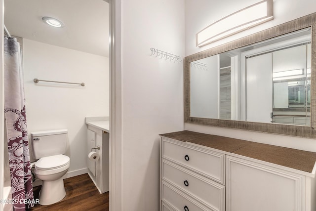 full bathroom featuring a shower with curtain, baseboards, toilet, wood finished floors, and vanity