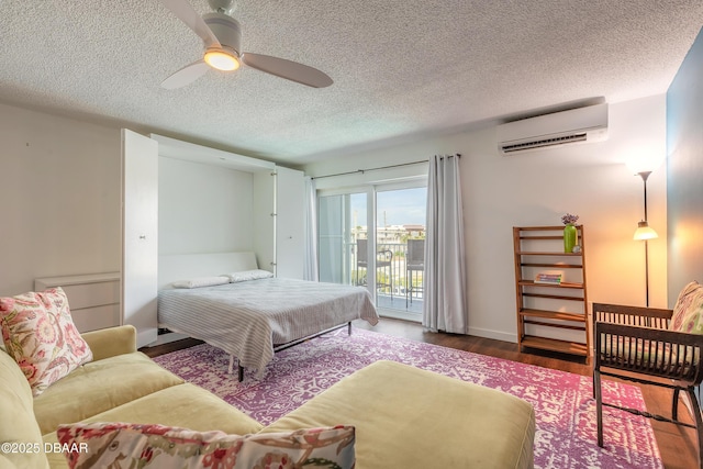 bedroom with a textured ceiling, a wall mounted AC, wood finished floors, a ceiling fan, and access to outside