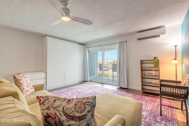 interior space featuring a textured ceiling, wood finished floors, a wall unit AC, and a ceiling fan