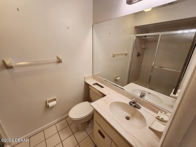 bathroom featuring toilet, vanity, tile patterned flooring, and a shower with door