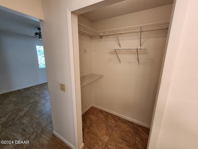 spacious closet featuring ceiling fan and dark tile patterned flooring