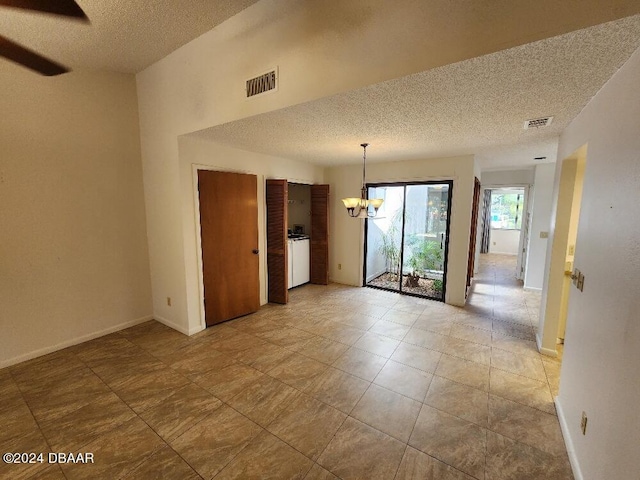 unfurnished room featuring a textured ceiling and an inviting chandelier