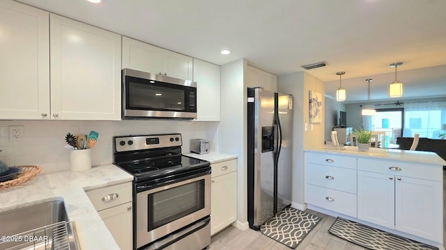 1275 Ocean Shore Blvd Unit 206, Ormond Beach, FL 32176 - kitchen with appliances with stainless steel finishes, a peninsula, a sink, white cabinets, and decorative backsplash