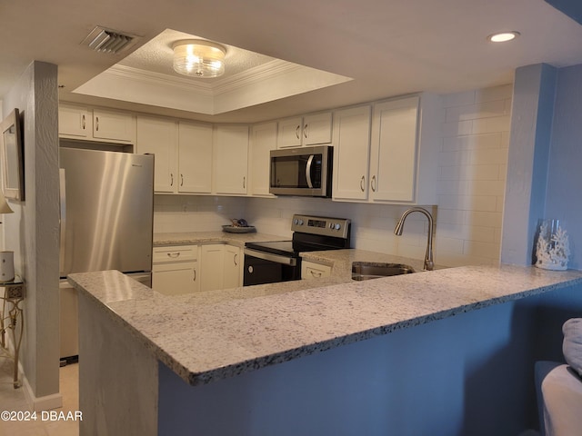 kitchen with white cabinetry, stainless steel appliances, a raised ceiling, and kitchen peninsula