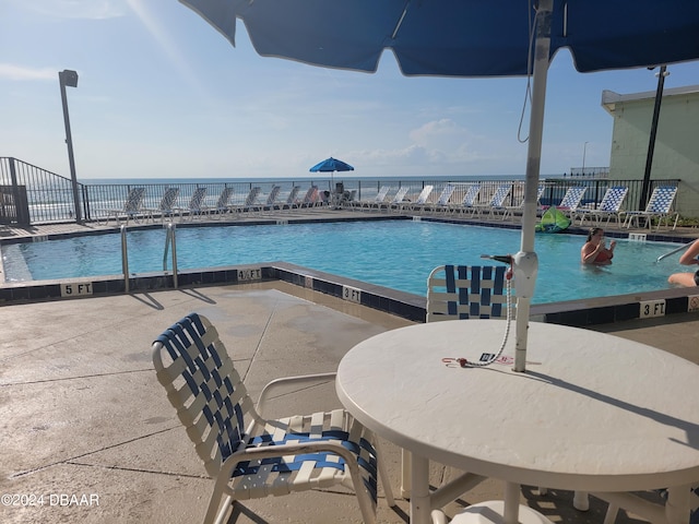 view of swimming pool with a water view and a patio area