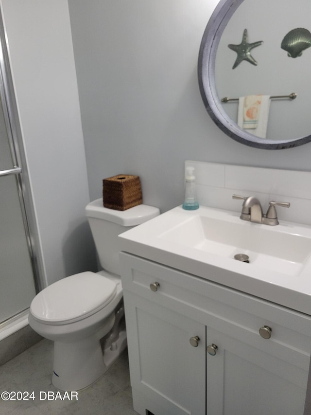 bathroom featuring vanity, toilet, a shower with door, and backsplash