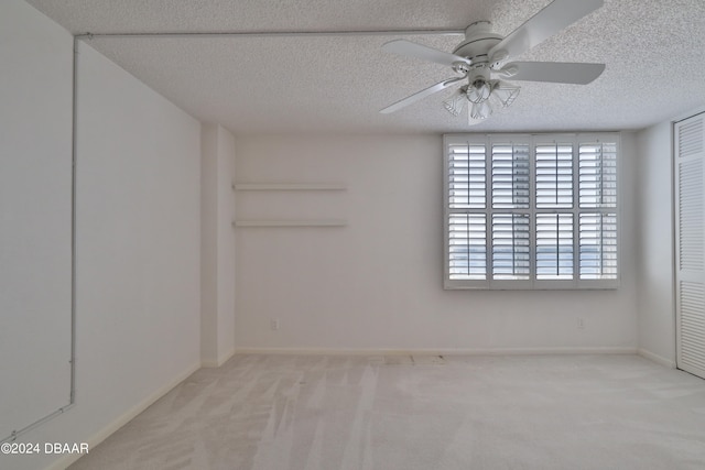 carpeted spare room with a textured ceiling and ceiling fan