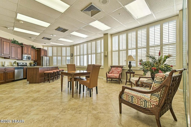 dining space with light tile patterned flooring and a drop ceiling