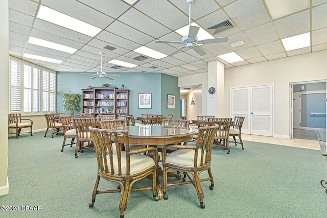 dining space featuring ceiling fan, light colored carpet, and a drop ceiling