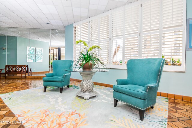 living area featuring parquet floors, a healthy amount of sunlight, and a paneled ceiling