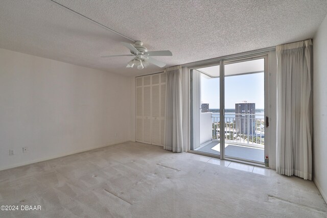 empty room with light colored carpet, a textured ceiling, and ceiling fan