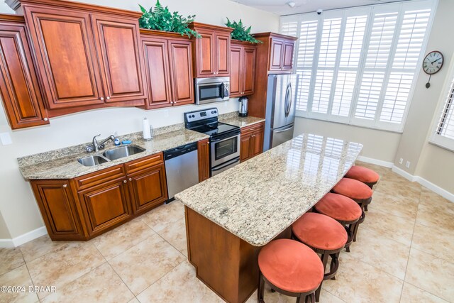 kitchen with a breakfast bar area, sink, appliances with stainless steel finishes, and a center island