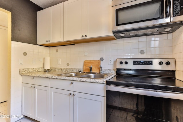 kitchen with stainless steel appliances, white cabinets, and sink