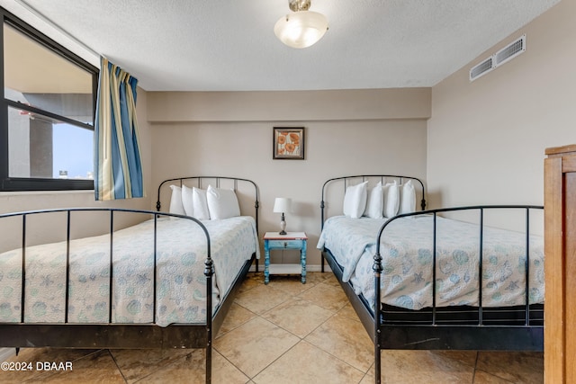 tiled bedroom featuring a textured ceiling