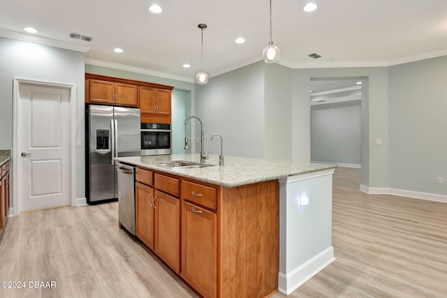 kitchen featuring light wood-type flooring, light stone countertops, an island with sink, and appliances with stainless steel finishes