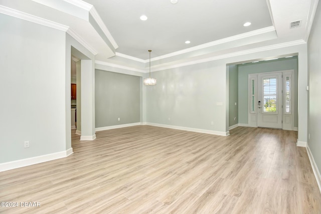 unfurnished living room featuring a tray ceiling, light hardwood / wood-style flooring, a chandelier, and ornamental molding