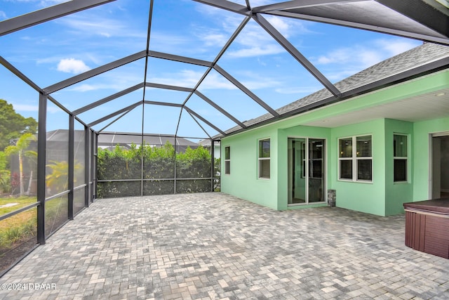 view of patio / terrace featuring glass enclosure and a jacuzzi