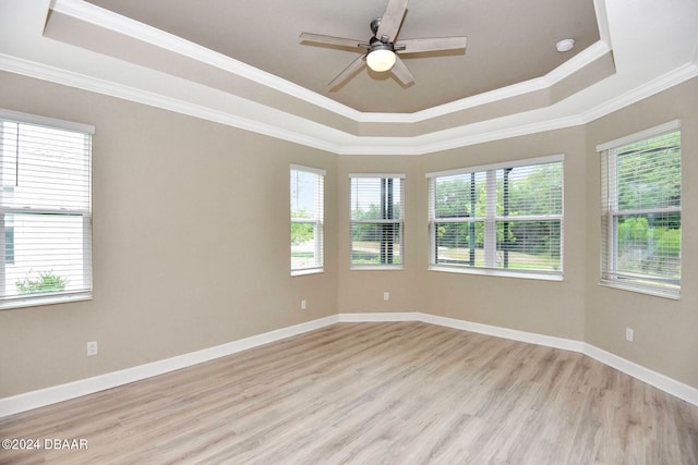 empty room with a raised ceiling, ceiling fan, light hardwood / wood-style floors, and ornamental molding