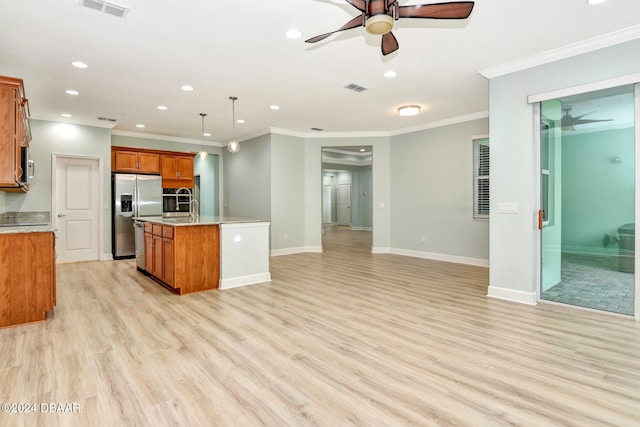 kitchen with decorative light fixtures, stainless steel appliances, light hardwood / wood-style floors, and a kitchen island with sink