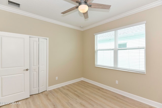 unfurnished bedroom featuring ceiling fan, light hardwood / wood-style floors, ornamental molding, and a closet