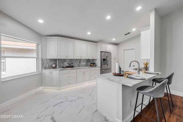 620 Middlebury Loop, New Smyrna Beach, FL 32168 - kitchen with stainless steel refrigerator with ice dispenser, light stone counters, white cabinets, recessed lighting, and a breakfast bar
