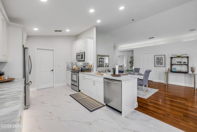 620 Middlebury Loop, New Smyrna Beach, FL 32168 - kitchen featuring appliances with stainless steel finishes, light stone counters, white cabinetry, recessed lighting, and a peninsula
