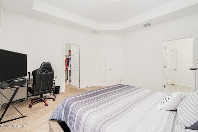 bedroom featuring a tray ceiling and light carpet