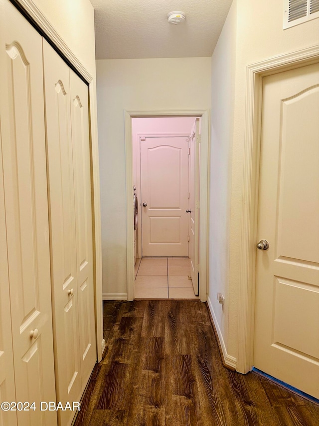 hallway with dark wood-type flooring and a textured ceiling