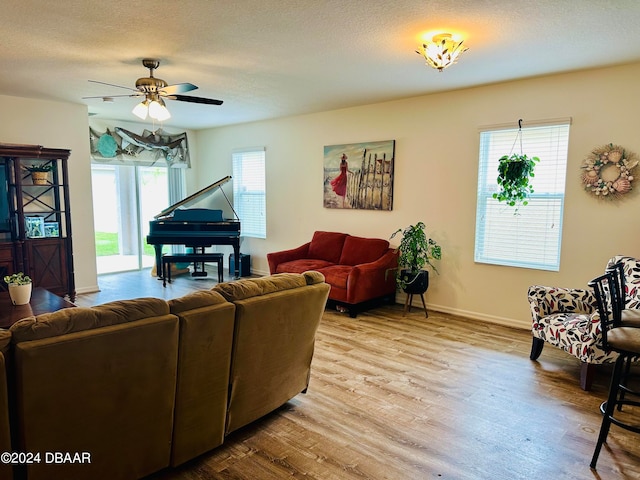 living room with ceiling fan, a textured ceiling, and light hardwood / wood-style floors