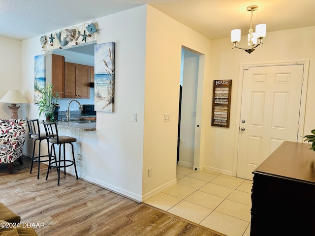 foyer with an inviting chandelier, sink, and light hardwood / wood-style flooring